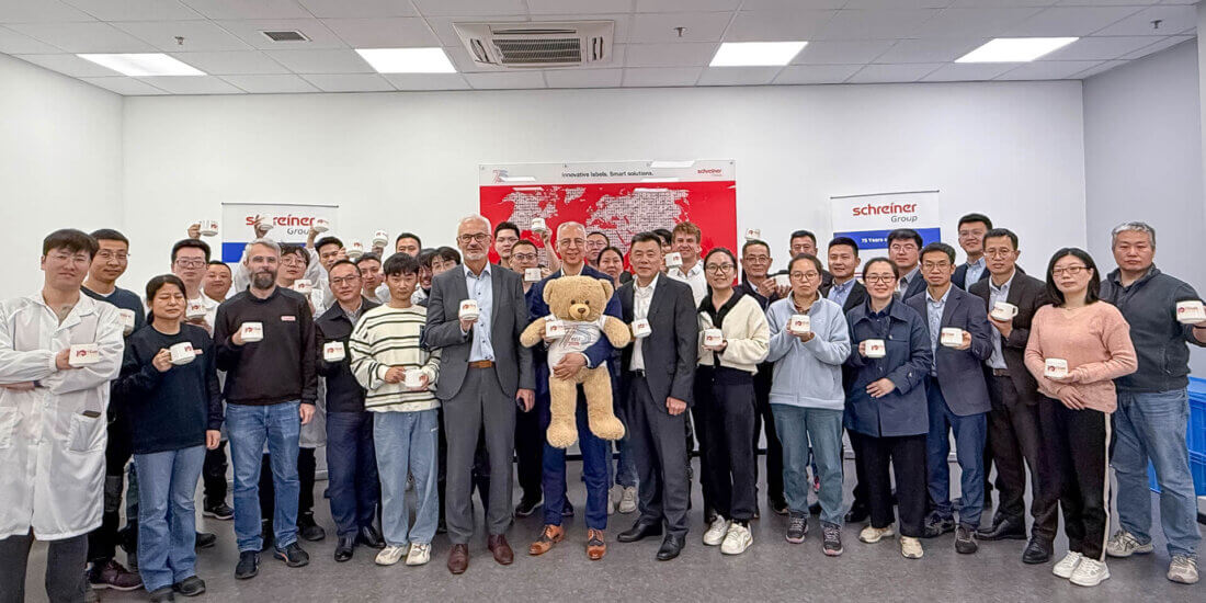 The workforce of Schreiner Group’s Chinese site celebrates the 10th anniversary together with Roland Schreiner (with the anniversary mascot “Bärli”) and Thomas Köberlein.