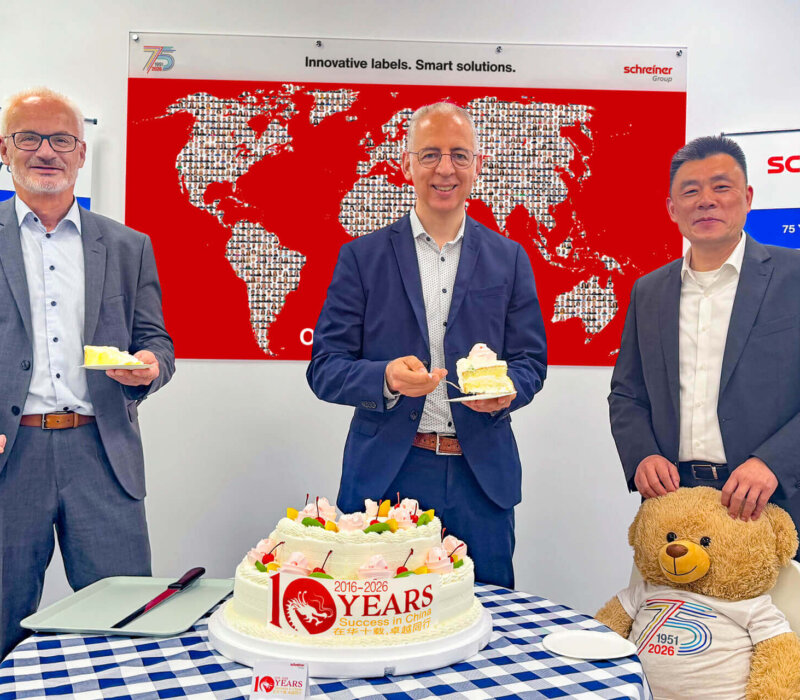 Geschäftsführer Roland Schreiner (Mitte), Thomas Köberlein (links), Geschäftsbereichsleiter Schreiner ProTech, und Jamie Long (rechts), General Manager der Schreiner Group (Shanghai) Company Ltd., schneiden die Jubiläumstorte an.