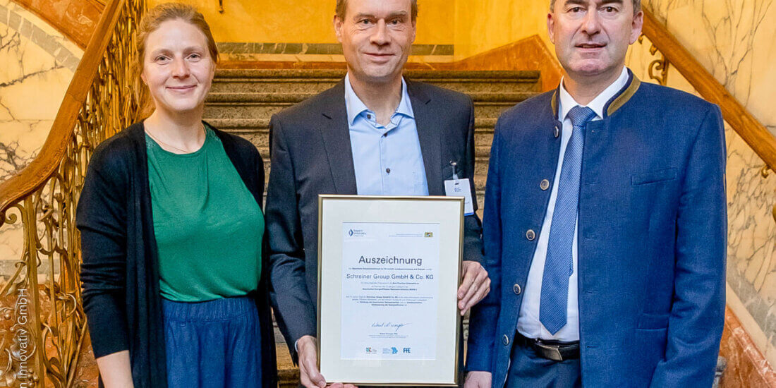 Zehn Jahre BEEN-i: Schreiner Group geehrt Dr. Thomas Gulden (Mitte) mit Dr.-Ing. Anna Gruber (l.), Geschäftsführerin der FfE und Wirtschaftsminister Hubert Aiwanger (r.) nach der Verleihung.